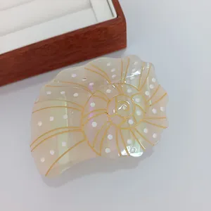 Détail macro d'une pince à cheveux en forme de conque en acétate avec finition irisée perle
