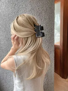Rear view of a gold-haired woman wearing a black glossy shark hair clip with white text