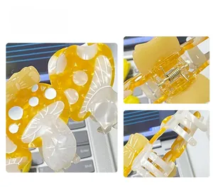 Detail of yellow mushroom hair claw clip with acetate finish and metal spring hinge