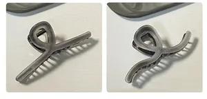Dettaglio di pinze per capelli in acetato grigio fumo con fitti denti neri su fondo bianco