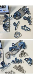 Dettaglio di varie pinze per capelli in acetato con motivi in marmo blu su una scrivania