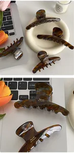 Macro detail of tortoiseshell acetate hair claw clip with gold lettering on a desk