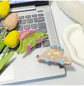 Dettaglio di mollette per capelli a forma di dinosauro in acetato verde e rosa su tastiera