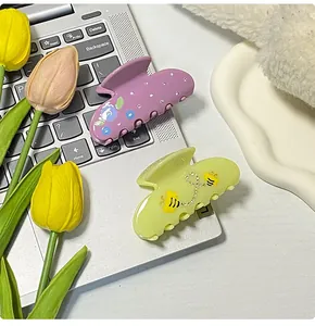 Haarklammern aus Acetat mit Blumen- und Bienenmuster und Strass auf einer Tastatur