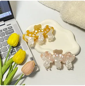 Detailed view of two mushroom hair claws in yellow and pink acetate with pearl finish