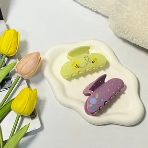 Blumige Haarklammern aus Acetat in Pastellviolett und Grün auf weißem Keramiktablett