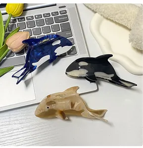 Drei Haarklammern in Walform aus Acetat in Blau, Schwarz und Beige auf einem Tablett