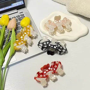 Whimsical mushroom acetate hair claws in four vibrant colors on a creative desk setting