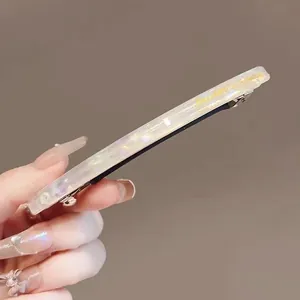 Détail d'une pince à cheveux en acétate avec paillettes et texte doré imprimé