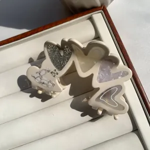 Detail of heart-shaped acetate hair claw with glitter and marble textures and rhinestones