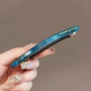 Détail de la barrette bleue en acétate avec texte Barrette la France doré sur métal