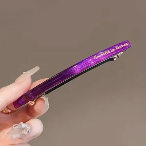 Détail macro d'une barrette en résine violette scintillante avec inscription dorée