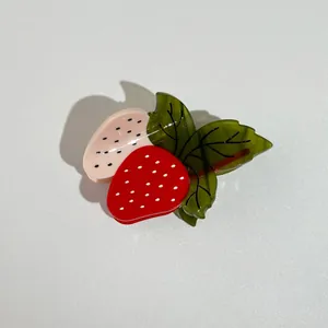 Détail de la pince à cheveux en acétate en forme de fraise avec texture rouge et rose