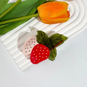 Détail d'une pince à cheveux en forme de fraise rouge en acétate sur un support décoratif