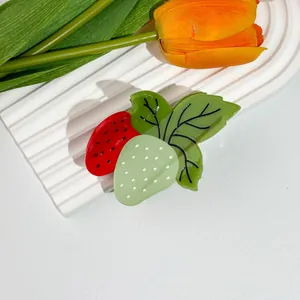Détail de pinces à cheveux fraises sur un plateau décoratif avec fleurs printanières