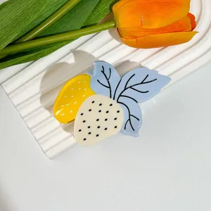 Détail macro d'une pince à cheveux fraise en acétate coloré avec des pois noirs