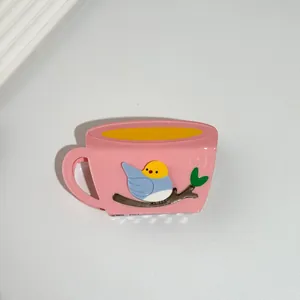 Detail of creative pink coffee cup hair claw clip with a colorful small bird design