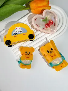 Dettaglio del set di quattro mollette per capelli con orsetto giallo e motivi a cuore