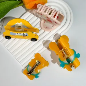 Mollette per capelli in acetato a forma di orso e auto su superficie bianca pulita