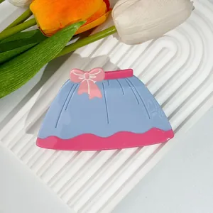 Detail of blue acetate hair claw clip in dress shape with pink bow on white stand