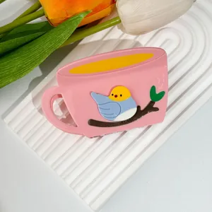 Detail of pink coffee cup hair claw clip featuring a 3D cartoon bird and floral background