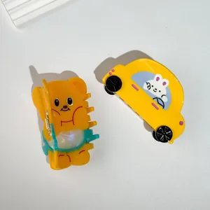 Dettaglio di mollette per capelli in acetato giallo a forma di orso e auto carina