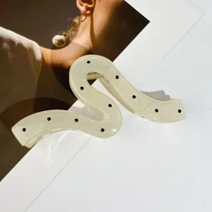 Détail macro d'une pince à cheveux en forme de S à pois avec finition résine brillante