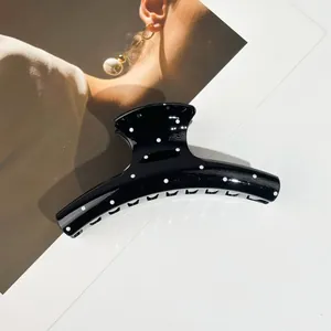 Grande pince à cheveux noire à pois blancs pour cheveux épais sur fond de mode élégant