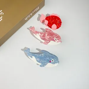Whale and goldfish shaped acetate hair claws in red, pink, and blue marble patterns