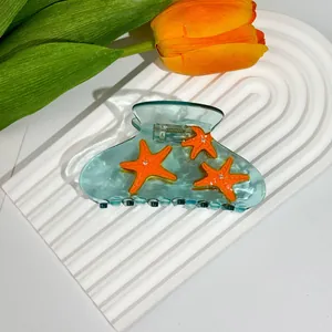 Detail von transparent-blauer Haarklammer mit orangefarbenen Seesternen und Strass