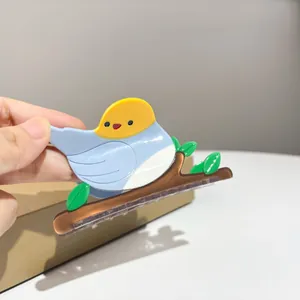 Detail view of a cute bird-shaped acetate hair claw clip held in hand for size