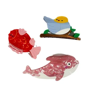 Whale and bird shaped acetate hair claws with iridescent pearlescent finish on white background