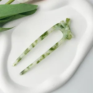 Detail view of large green marble acetate U-shaped hair pin with elegant bow design