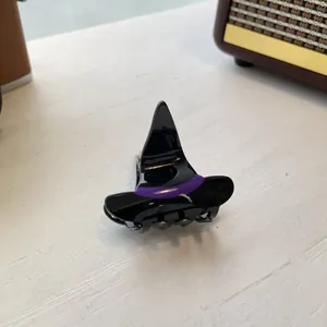 Detail of a witch hat Halloween hair claw clip in black and purple acrylic on a desk