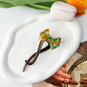Detail einer Bananenspange mit grüner Schildpatt-Schleife auf Keramiktablett