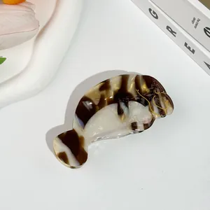 Détail d'une pince à cheveux en forme de lamantin avec motif marbré brun en acétate