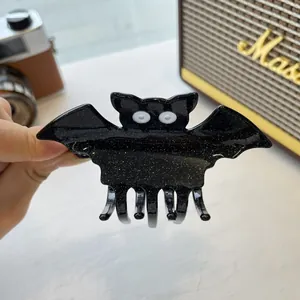 Detail of black glittery bat hair claw clip with white eyes for Halloween styling