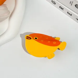 Détail macro d'une pince à cheveux poisson-globe en acétate brillant jaune et orange