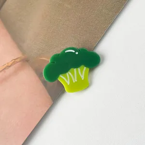 Gros plan sur une pince à cheveux en acétate en forme de brocoli vert avec des motifs