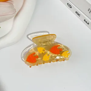 Détail de la pince à cheveux en acétate avec motifs de poissons tropicaux colorés sur fond blanc