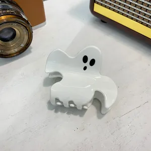 Close-up of white acrylic ghost hair claw clip for Halloween on a vintage background