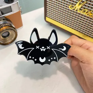 Detail of a black acrylic bat hair claw clip with celestial star and moon patterns