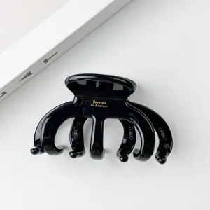 Detail einer schwarzen Haarklammer aus Acetat mit goldener Barrette La France Aufschrift