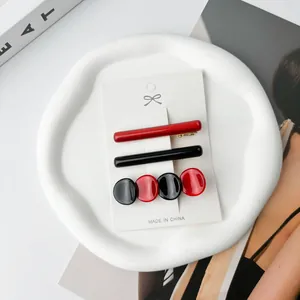 Detail view of three minimalist red and black acetate hair clips on a white display card