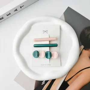 Detailed set of acetate hair clips in pink and green displayed on a marble tray