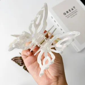 Iridescent white butterfly acetate claw clip for hair styling shown in hand