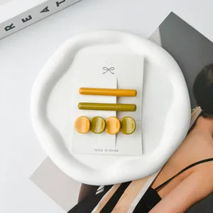 Close-up of a three-piece acetate hair clip set in ginger yellow and olive green tones