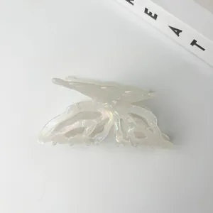 Macro shot of iridescent white butterfly hair claw clip with delicate cutout texture
