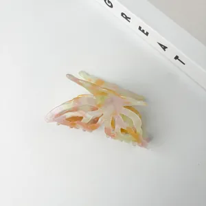 Close-up of butterfly hair claw with iridescent marble texture on minimalist white background