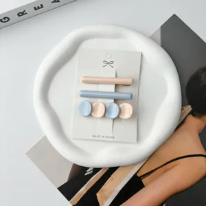 Detailed view of pastel resin hair clips in pink and blue on a white ceramic tray